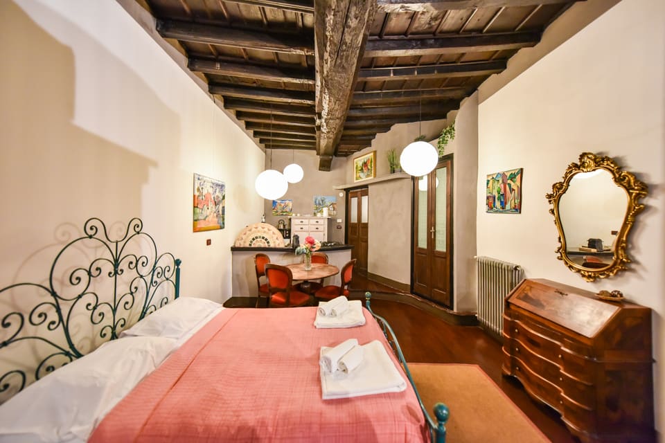 Il letto in ferro battuto e, oltre, la zona pranzo e l'angolo cottura