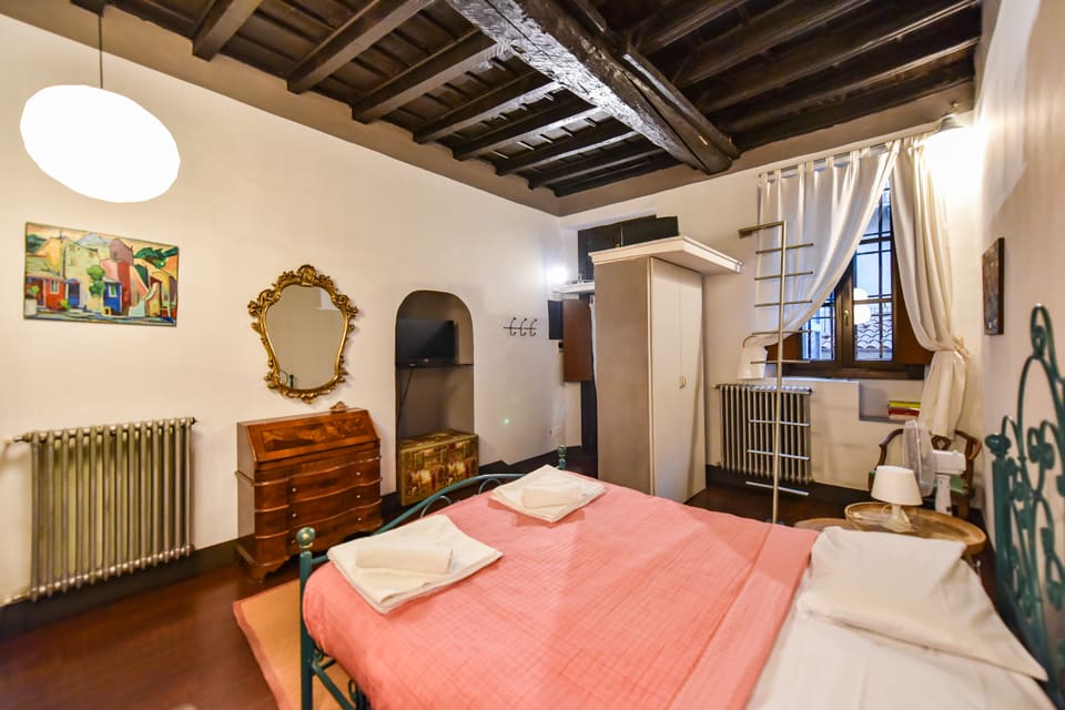 Letto matrimoniale con testiera in ferro battuto e mobili d'epoca